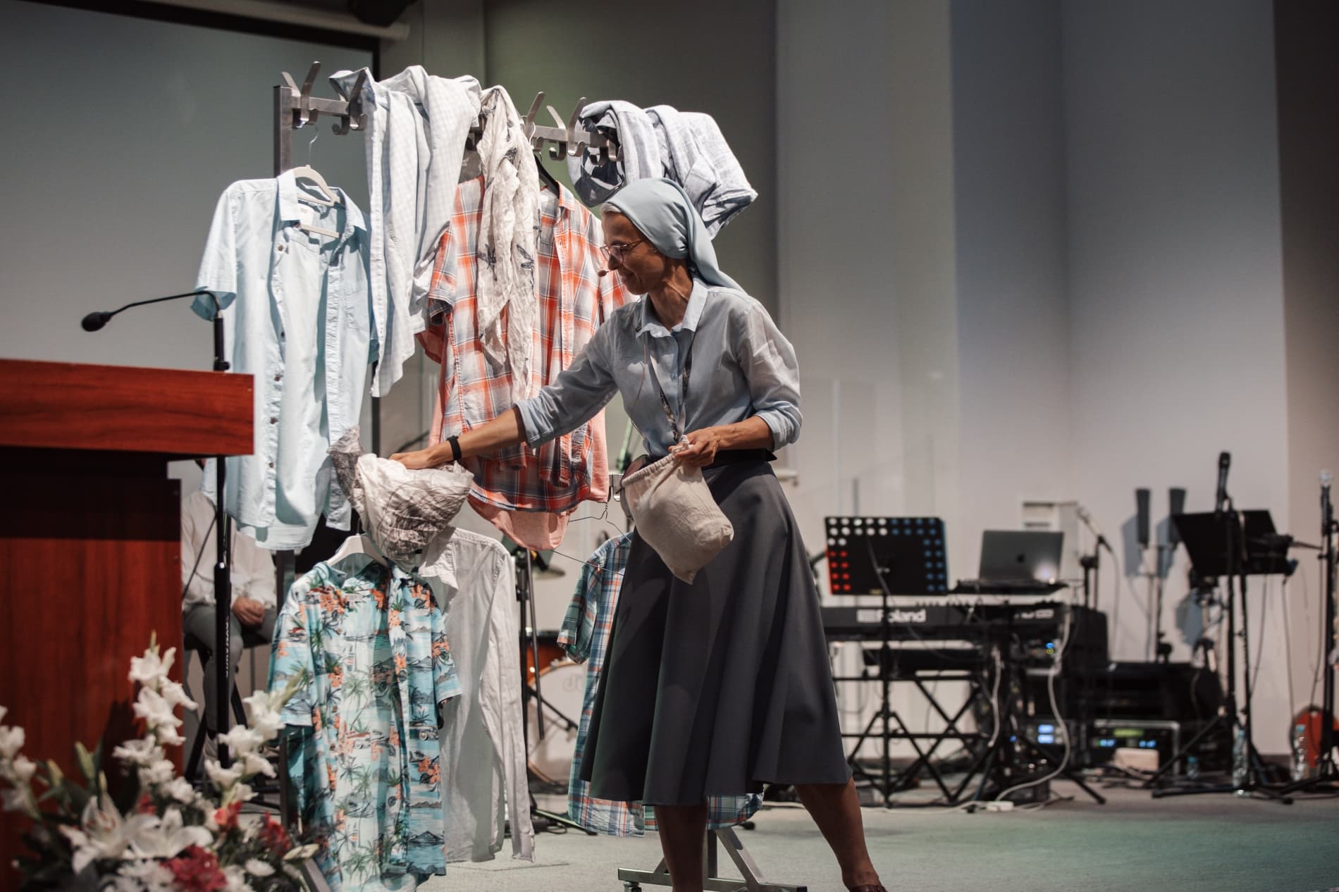 Siostra zakonna pokazuje na wieszakach ubrania (mówi konferencję, ma przy ustach mikrofon)